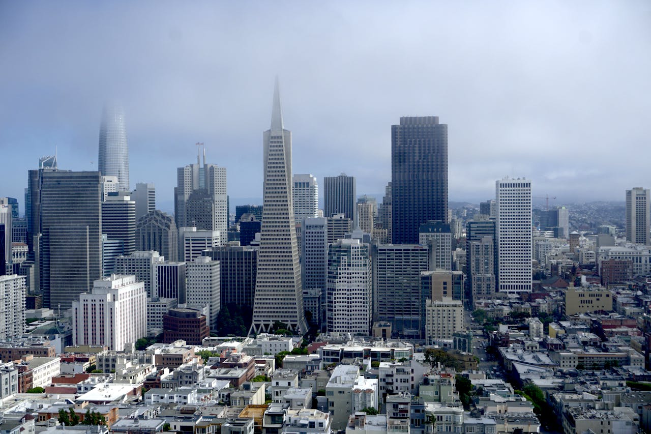 Panoramic aerial view of San Francisco's iconic skyline with fog and clouds.