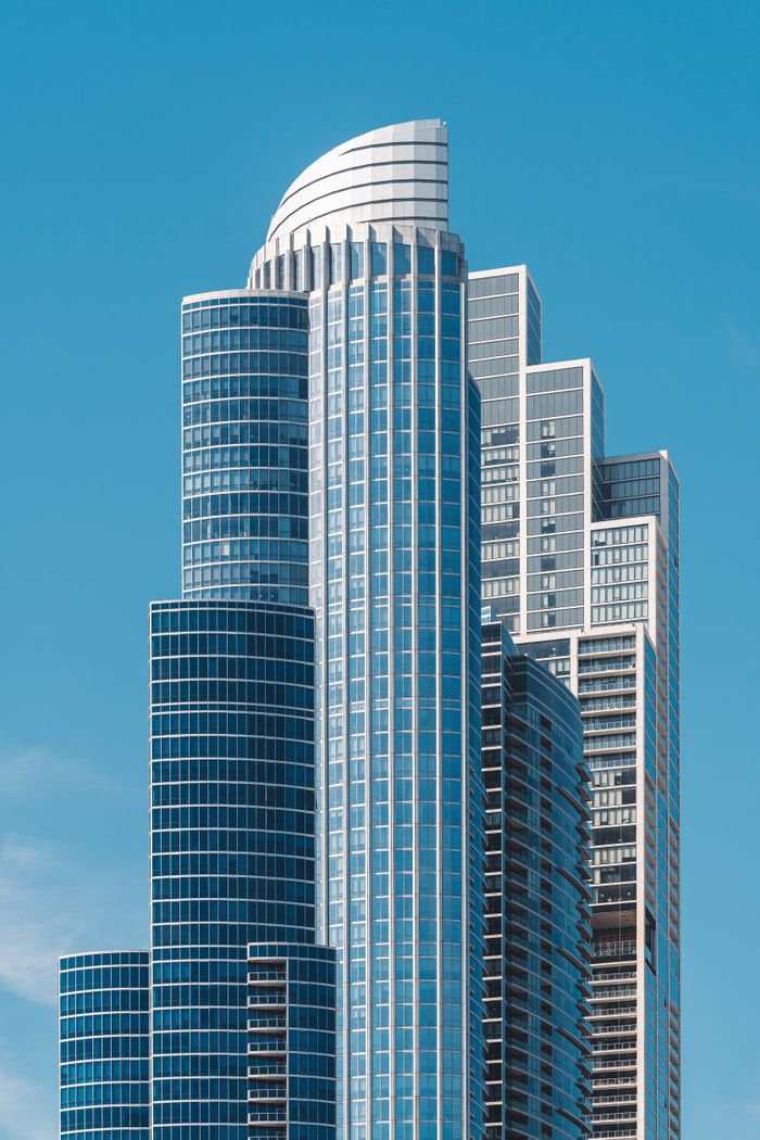 Tall modern skyscraper with glass facade against a clear blue sky.